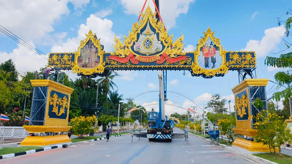 ภาพตัวอย่างลักษณะงาน: ซุ้มเฉลิมพระเกียรติสีน้ำเงินและทองคร่อมถนน มีรถเครนอยู่ระหว่างติดตั้ง