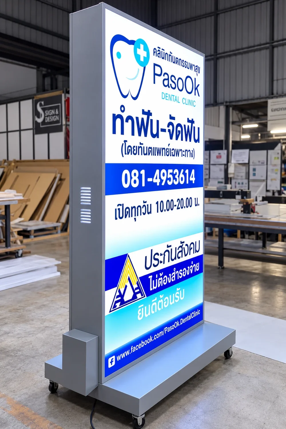 ภาพตัวอย่างลักษณะงาน: ป้ายไฟกล่องตั้งพื้นโครงสีเงินบนฐานติดล้อ หน้าป้ายพิมพ์โลโก้คลินิกทันตกรรม เบอร์โทร และเวลาเปิดทำการ